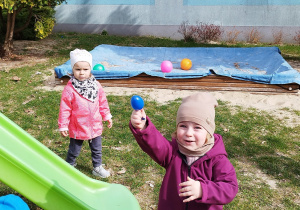 dziewczynka pokazuje znalezione jajko, inna dziewczynka patrzy