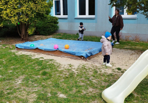 w oddali dzieci na podwórku szukają jajek