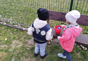 dzieci stoją przy wiaderku z jajkami