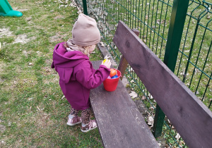dziewczynka wkłada znalezione jajko do wiaderka
