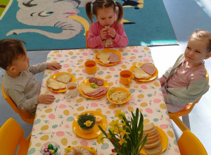 dzieci siedzą przy stole, na którym stoją pokarmy , kwiaty i dekoracje