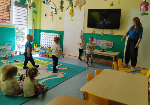 opiekunka pokazuje dzieciom globus