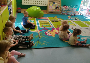 dzieci siedza na dywanie i słuchają informacji jak dbać i planetę