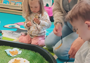 opiekunka wraz z dziećmi nawleka na druciki małe kółeczka