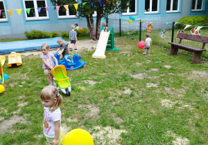 dzieci chodzą po podwórku i bawią się balonami