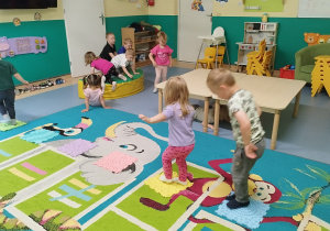 dzieci chodzą po rozłożonych płytkach sensorycznych