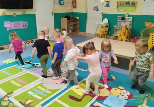 dzieci jedno za drugim chodzą po płytkach sensorycznych