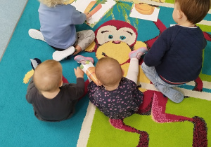dzieci siedzą na dywanie układają puzzle